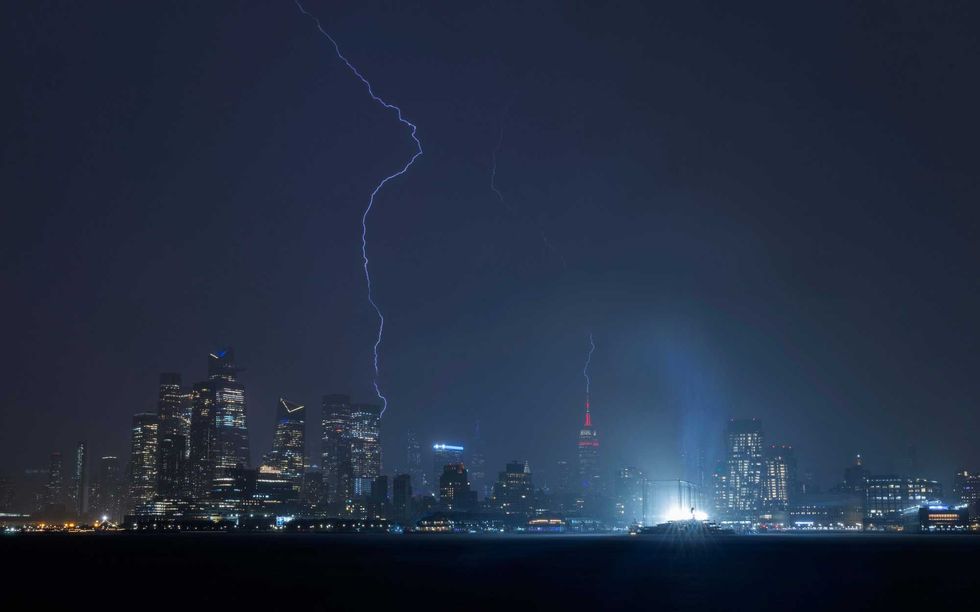Lightning strikes the Empire State Building and behind Hudson Yards in New York City during a thunderstorm on May 29, 2024, as seen from Hoboken, New Jersey