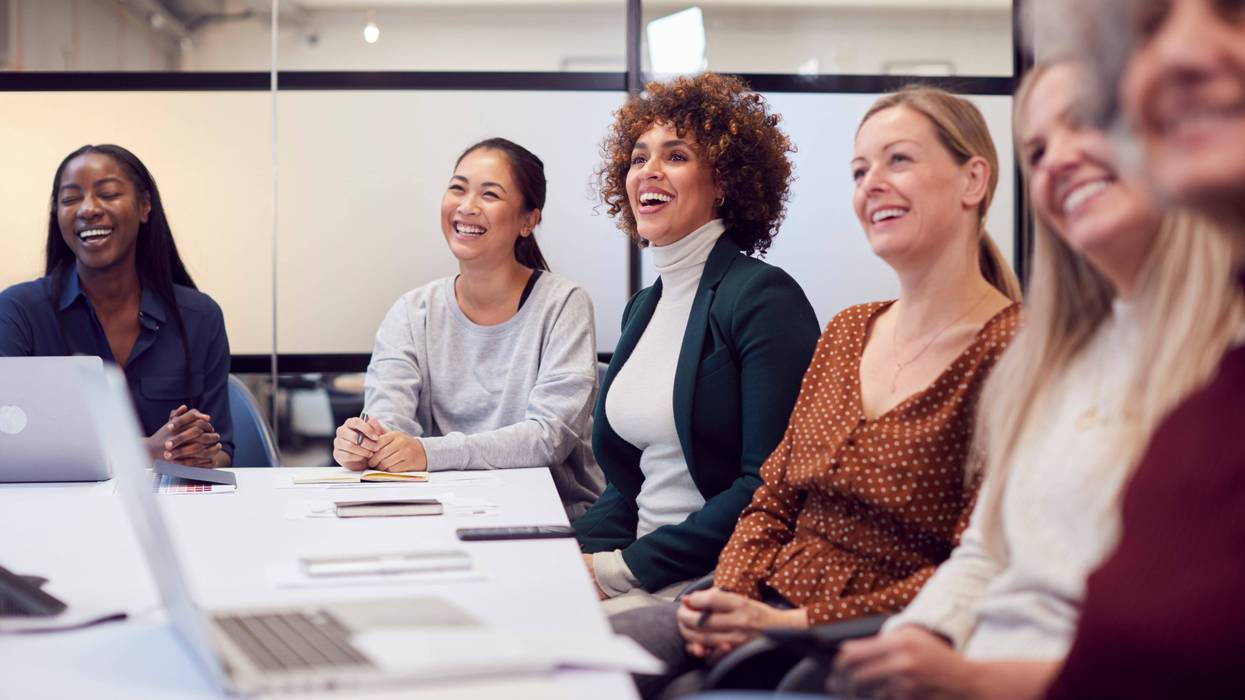 Line Of Businesswomen In Modern Office Listening To Presentation By Colleague