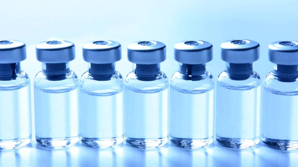 Line of clear glass medical vials containing vaccine or medication.