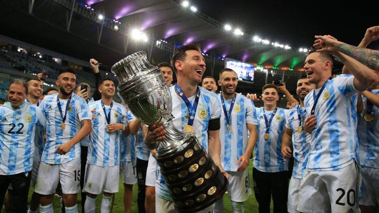 Lionel Messi of Argentina smiles with the trophy as he celebrates with teammates after winning the final of Copa America Brazil 2021 between Brazil and Argentina at Maracana Stadium on July 10, 2021 in Rio de Janeiro, Brazil.