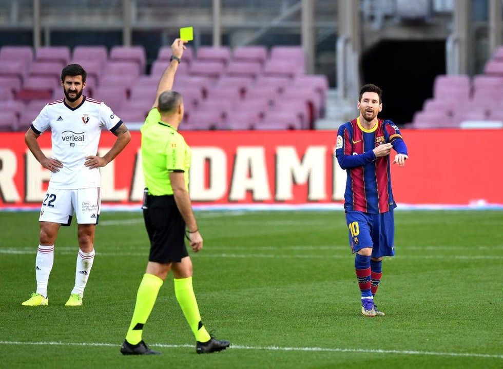 Lionel Messi of Barcelona is shown a yellow card after removing his shirt whilst celebrating after scoring their sides fourth goal while wearing a Newell