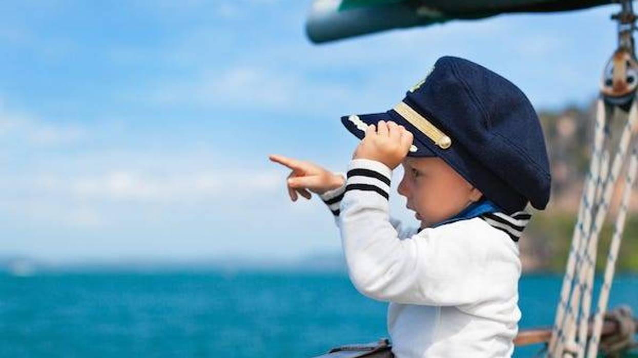 Little baby captain on board of sailing yacht