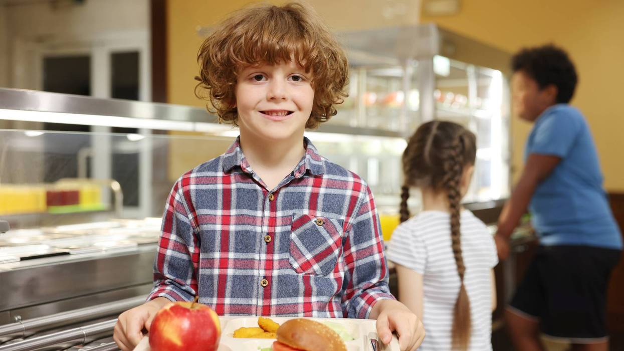 Little boy with tray of tasty food in school canteen, selective focus