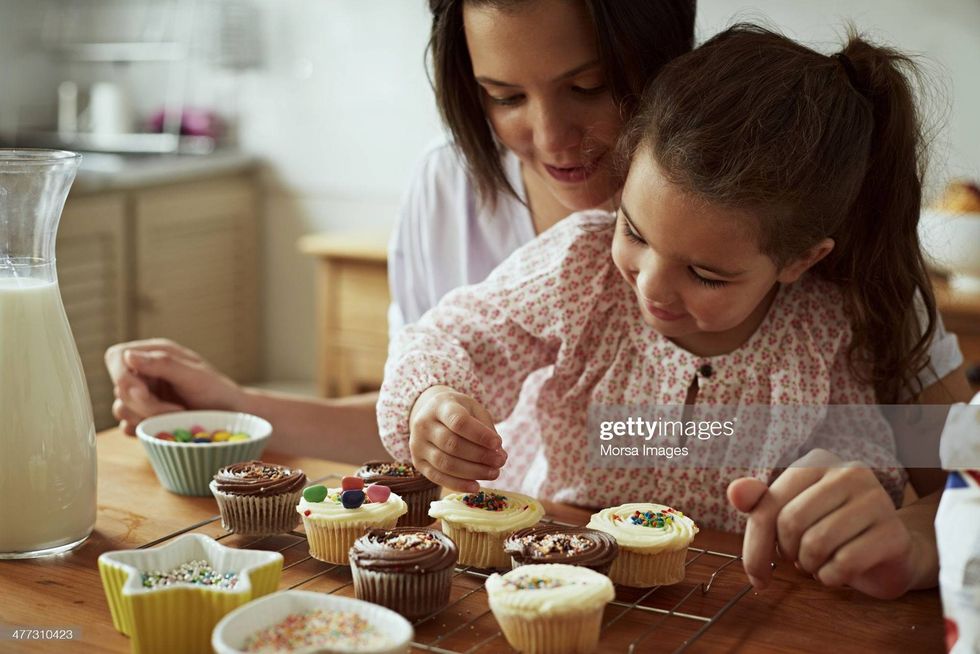 Little girl decorates cupcakes with help from her mom