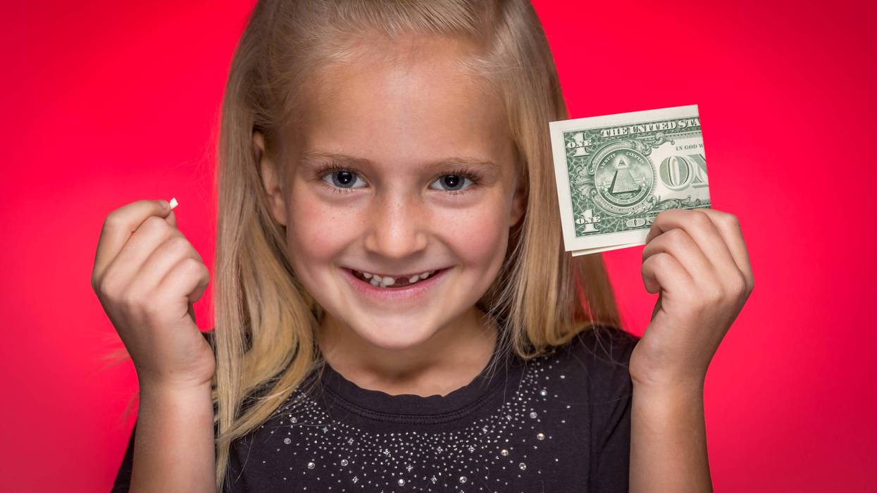 Little girl holding up a tooth and a dollar bill
