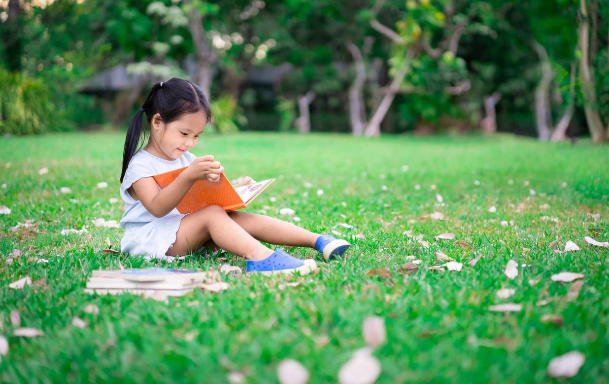 little girl reading in a field