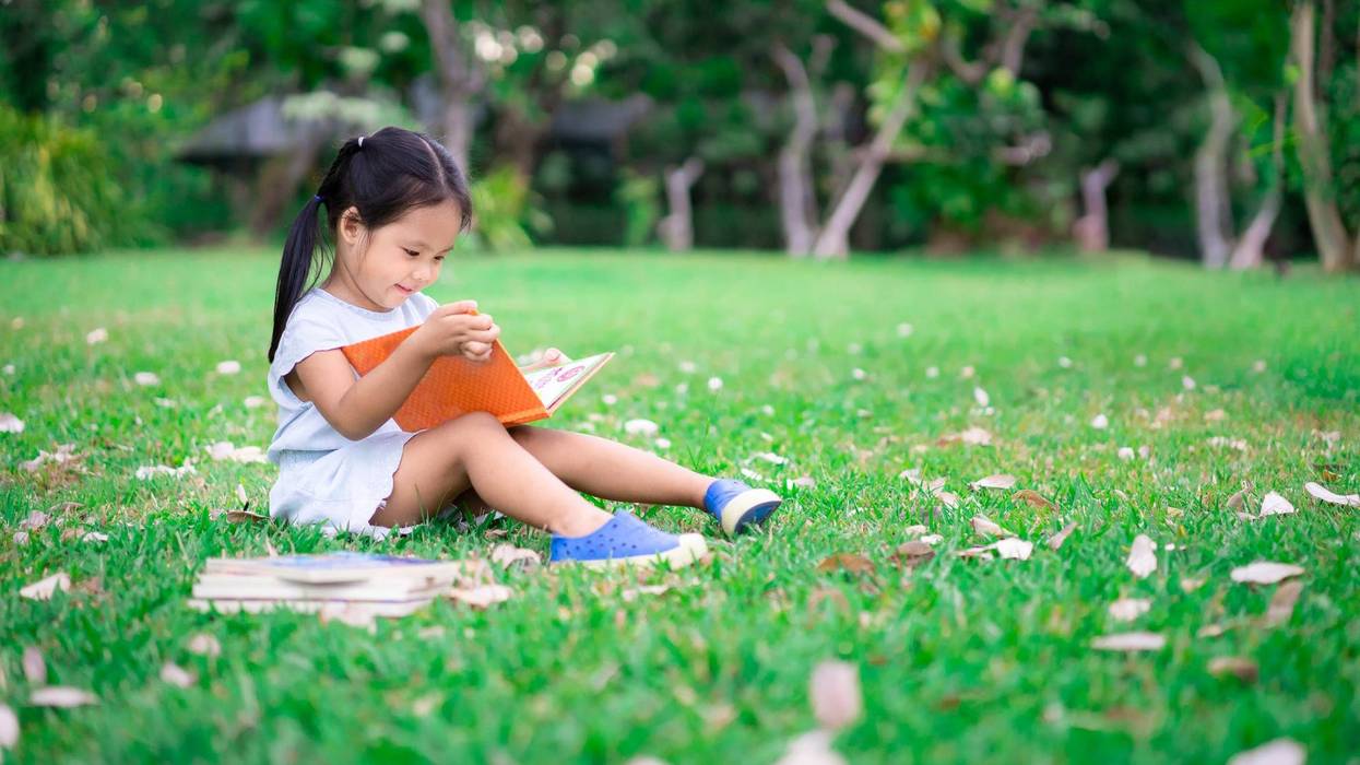 little girl reading in a field