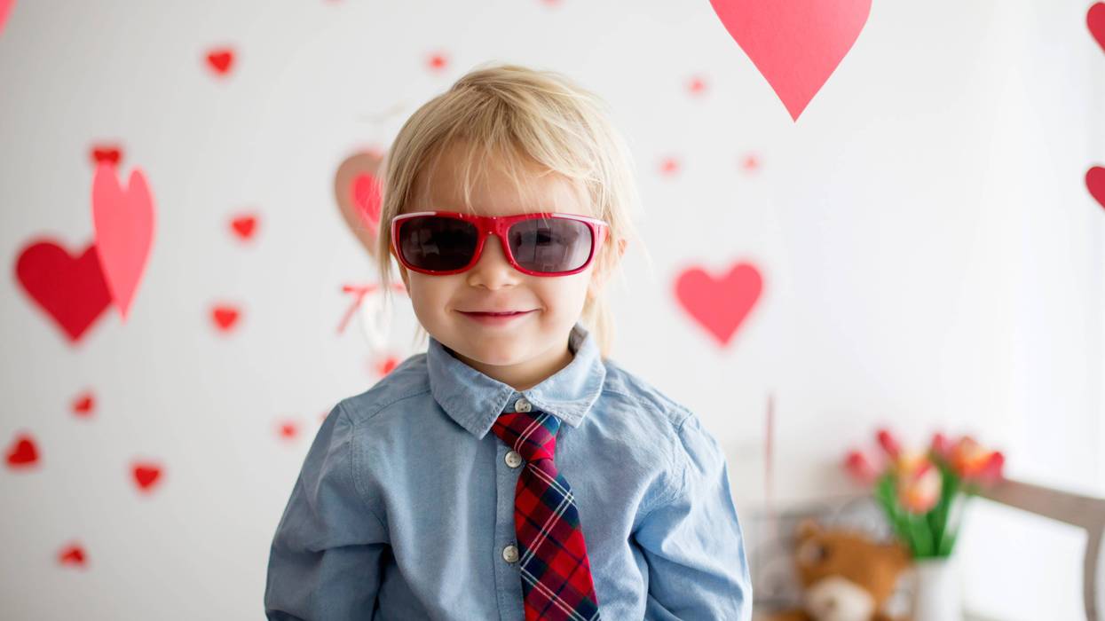 Little kid with Valentine's hearts behind him