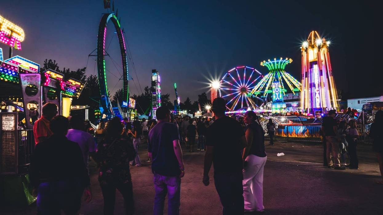 Lively night carnival with multiple brightly lit rides and people walking.