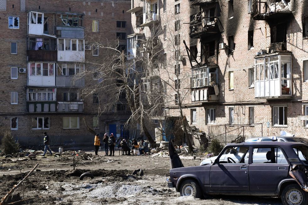 Local residents are seen outside an apartment block where the basement is used as a bomb shelter in the city of Volnovakha