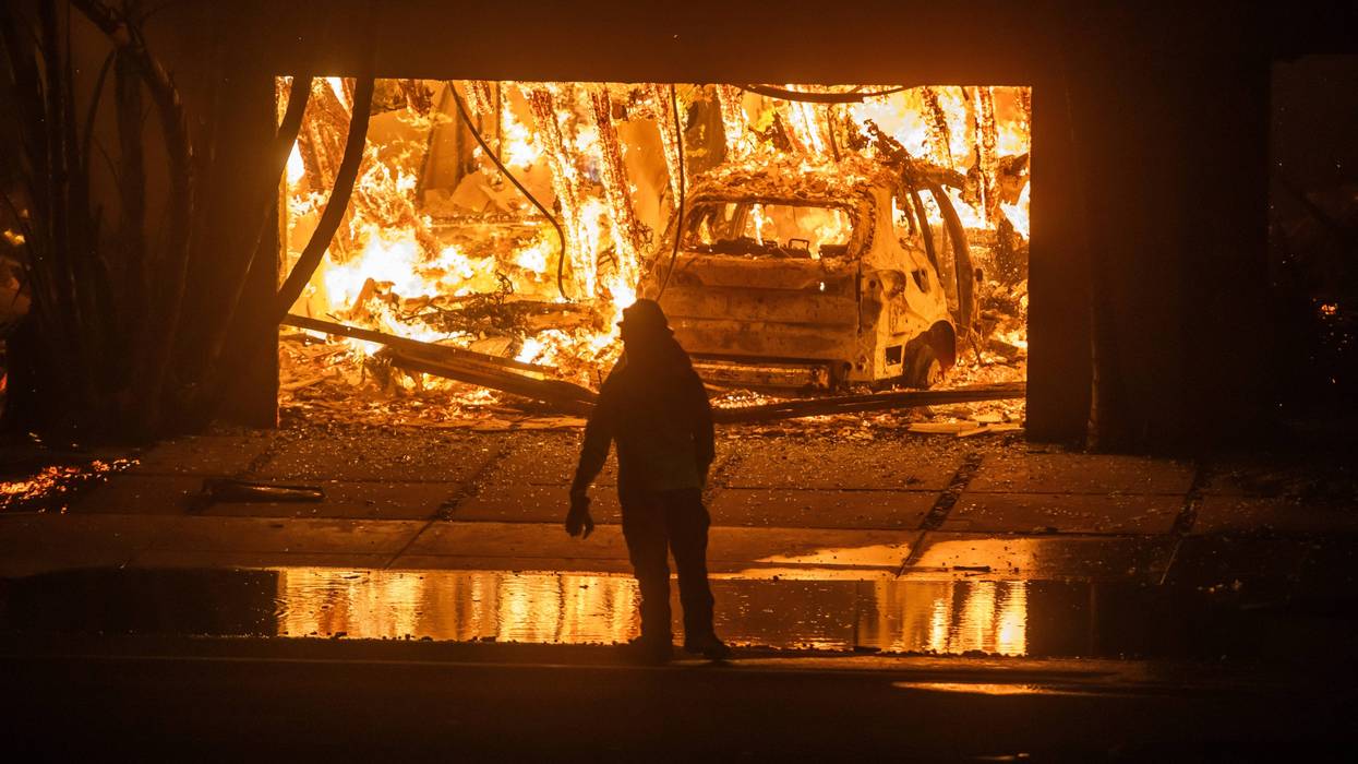 LOS ANGELES, CALIFORNIA - JANUARY 8: A firefighter watches the flames from the Palisades Fire burning homes on the Pacific Coast Highway amid a powerful windstorm on January 8, 2025 in Los Angeles, California. The fast-moving wildfire has grown to more than 2900-acres and is threatening homes in the coastal neighborhood amid intense Santa Ana Winds and dry conditions in Southern California.