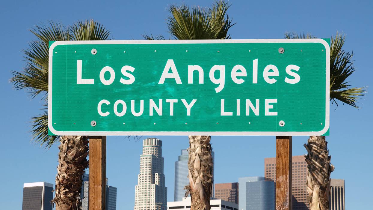 Los Angeles county line sign with downtown Los Angeles skyline in background.