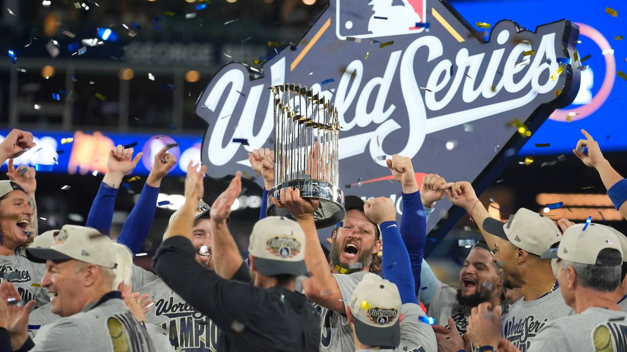 Los Angeles Dodgers pitcher Clayton Kershaw (22) celebrates with the Commissioner's Trophy on the podium after defeating the Toronto Blue Jays in the 2025 MLB World Series at Rogers Centre.