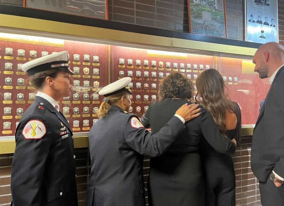 Loved ones and Chicago Fire Commissioner Annette Nance-Holt stand in front of the department