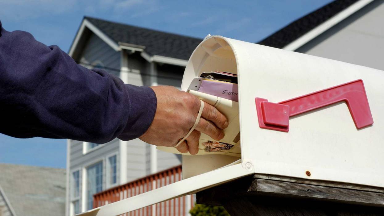 Mailman making a delivery into a mailbox.