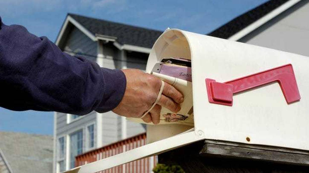 Mailman putting mail in a mail box.