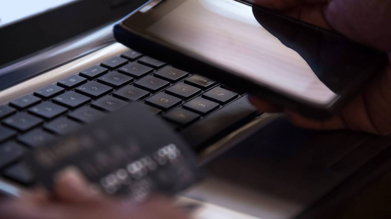 making purchase on phone, laptop in background