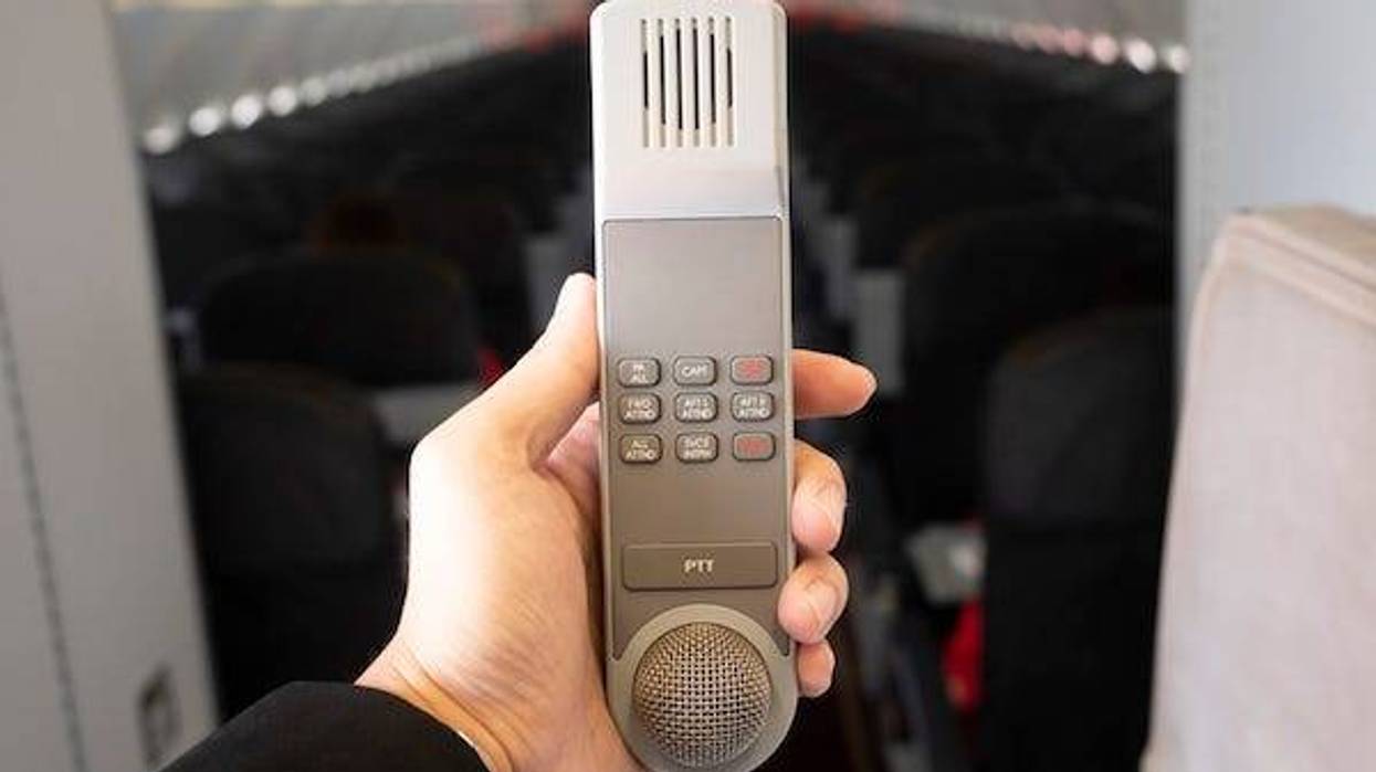 Male cabin crew holding interphone in aircraft cabin