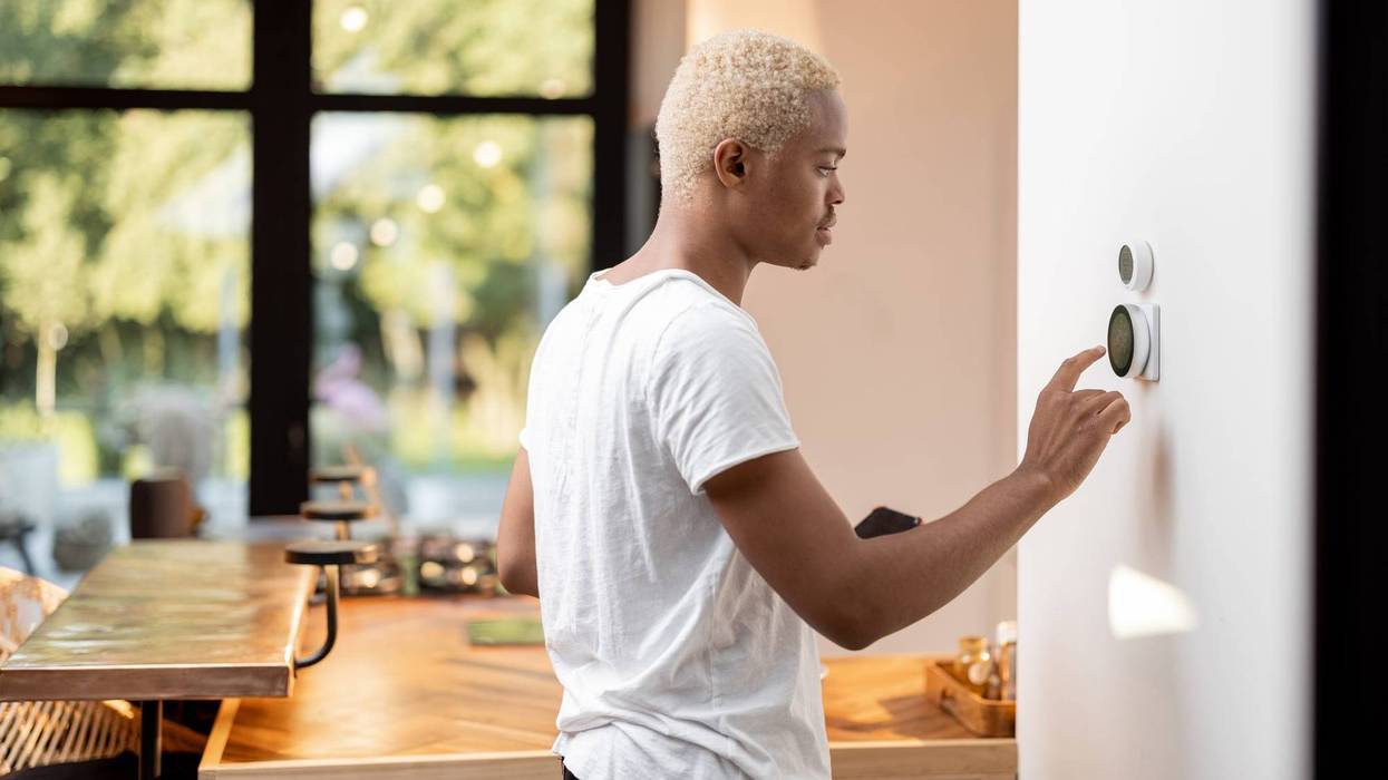 Man adjusts temperature on thermostat.