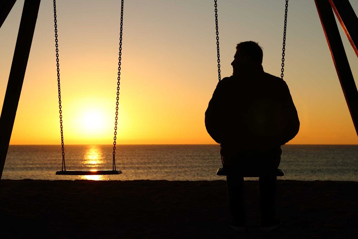 Man alone on a swing remembering someone he lost.