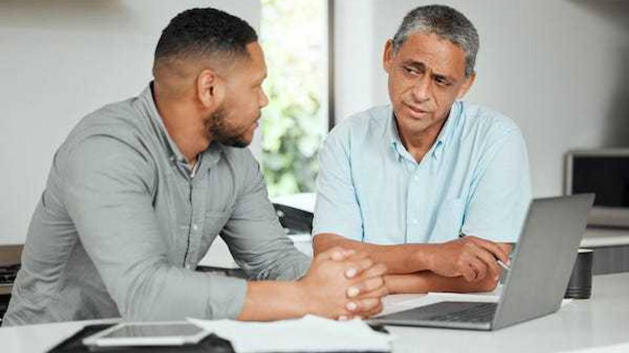 Man and his father working on a laptop at home