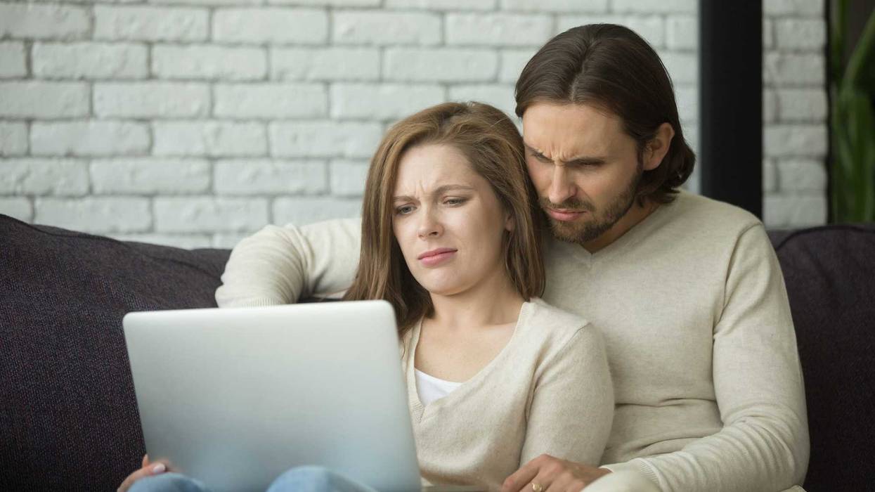 Man and woman looking confused at a laptop screen.