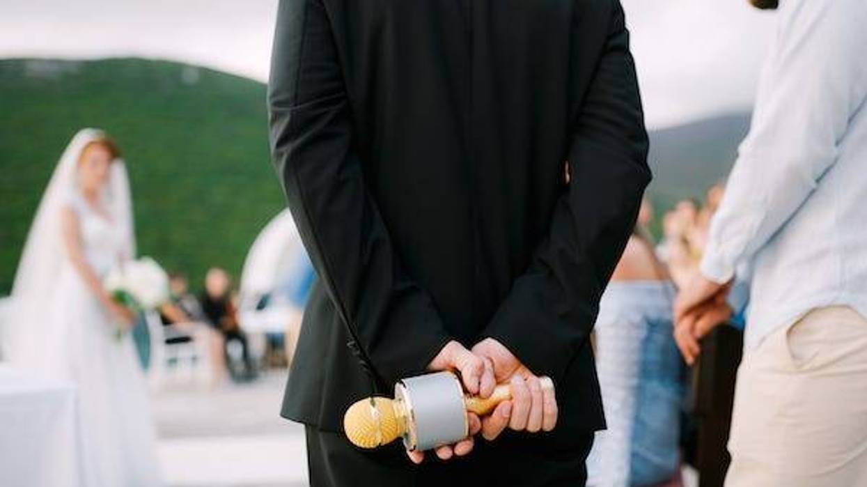 Man at wedding reception stands with microphone behind his back