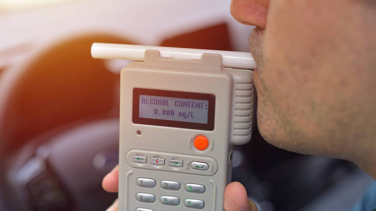 Man blows into breathalyzer in vehicle