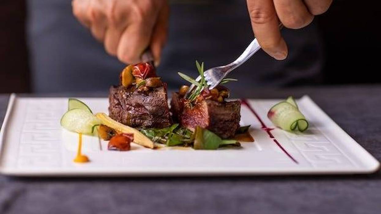 Man cutting a piece of steak with vegetables