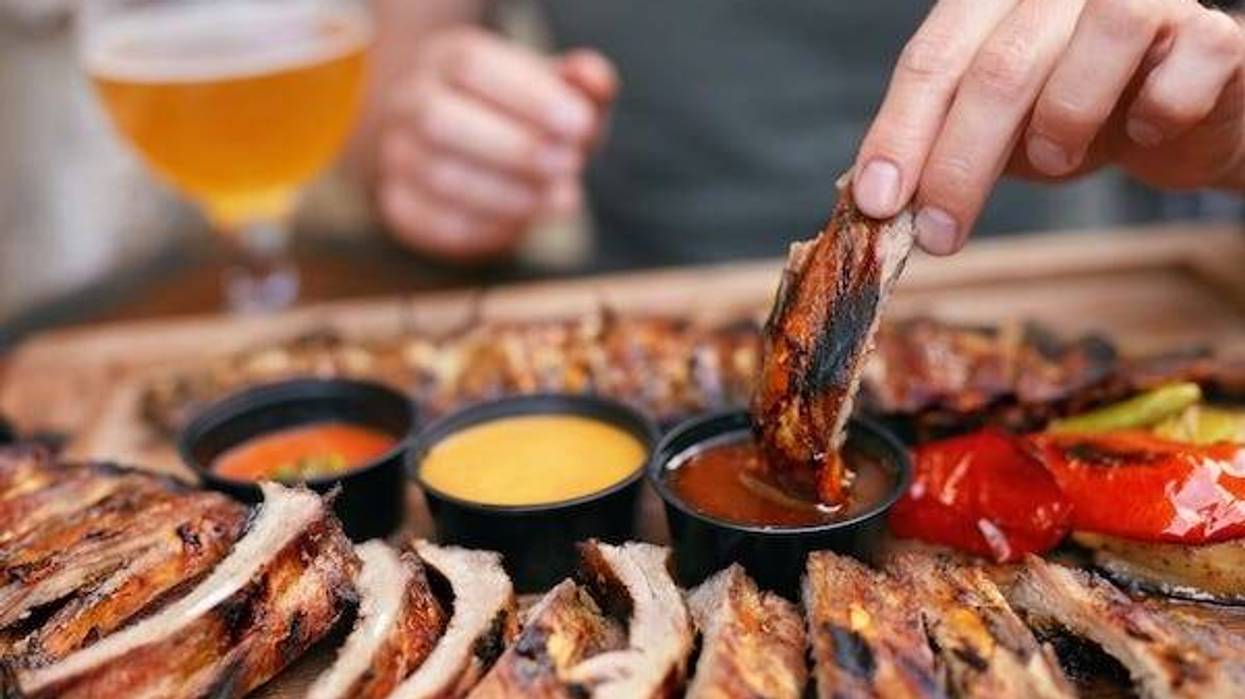 Man dipping a barbecue rib in sauce