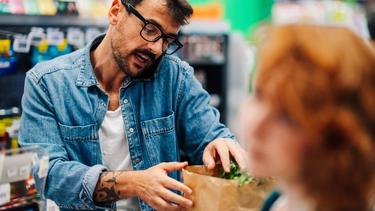 Man grabbing paper grocery bag from checkout