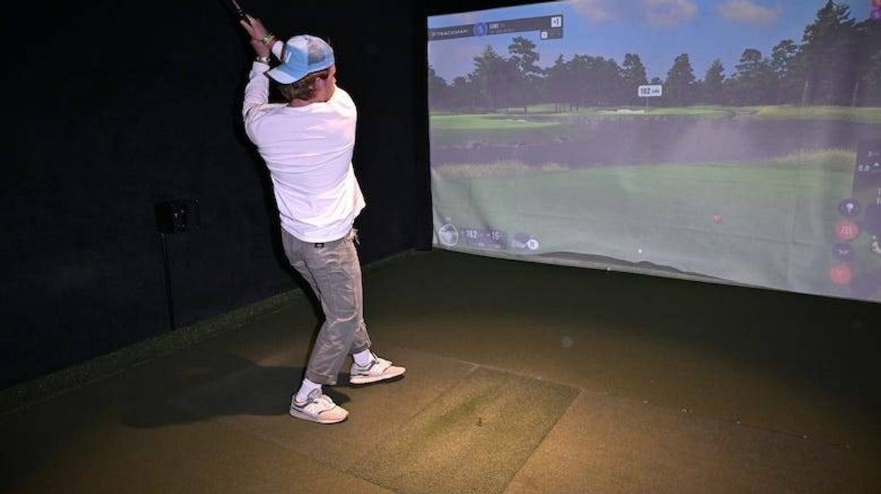 Man hitting a shot at a golf simulator