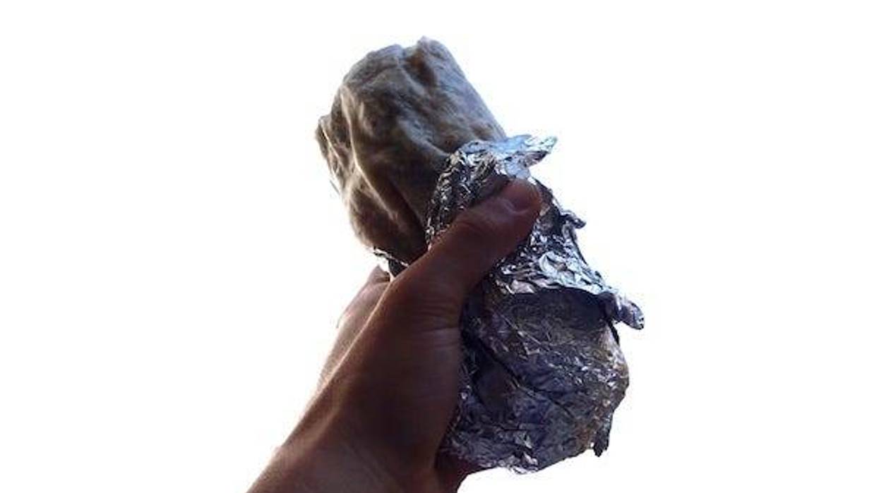 Man holding a burrito wrapped in tin foil