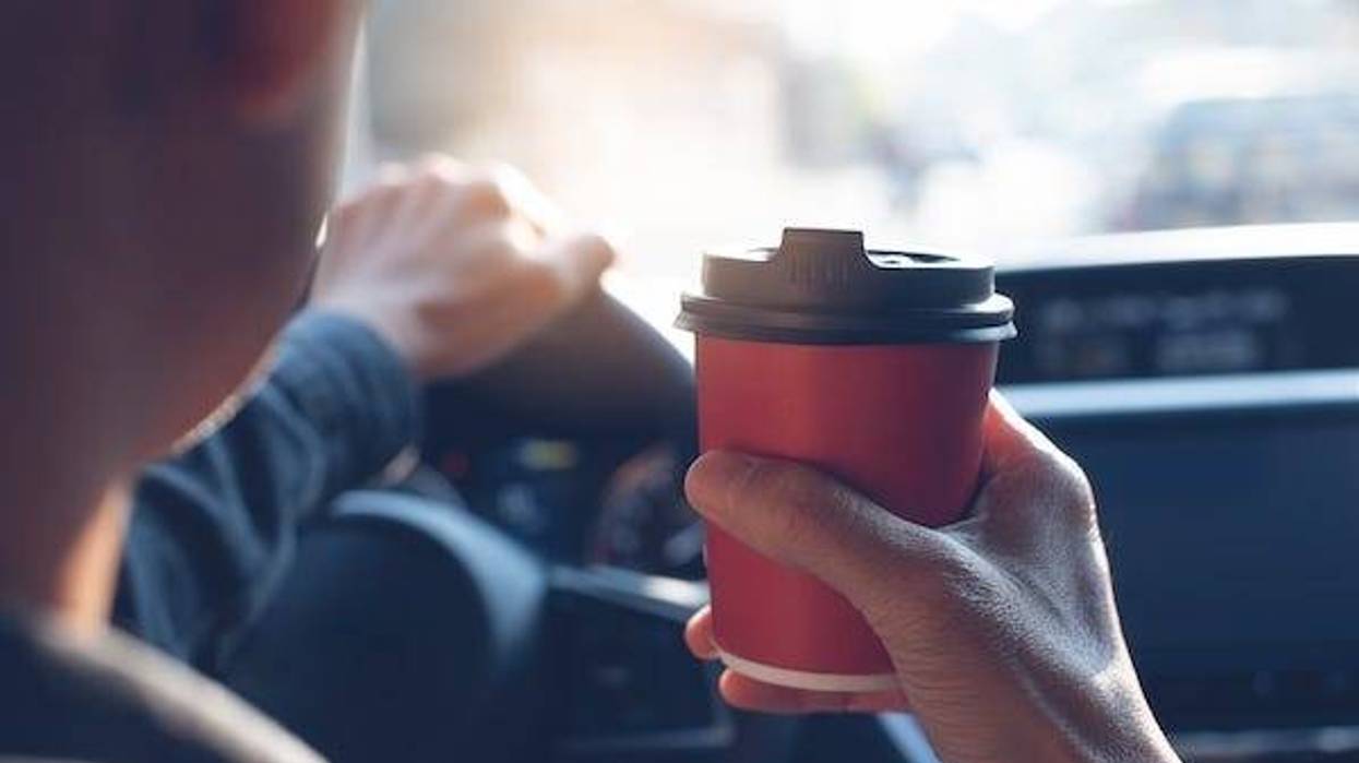 Man holding a cup of coffee while driving