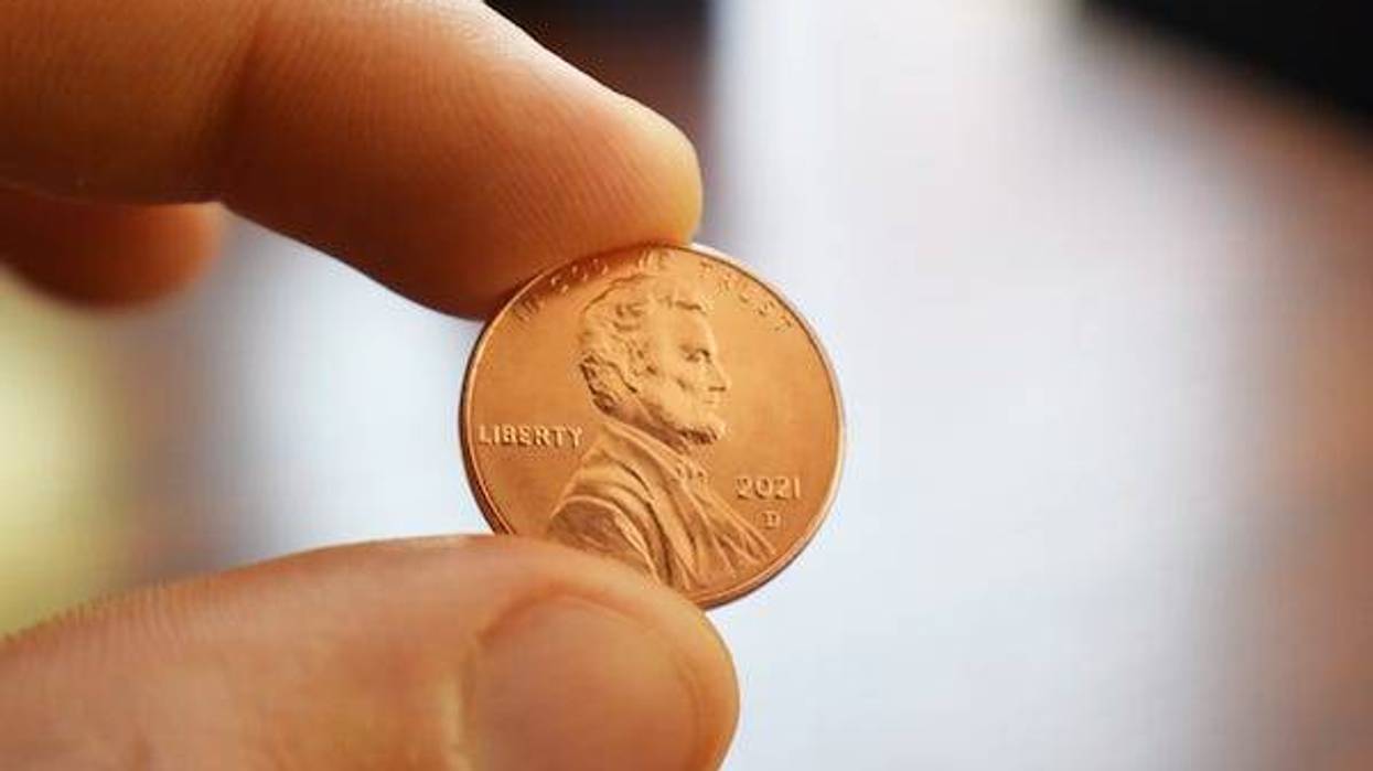 Man holding a penny in between fingers