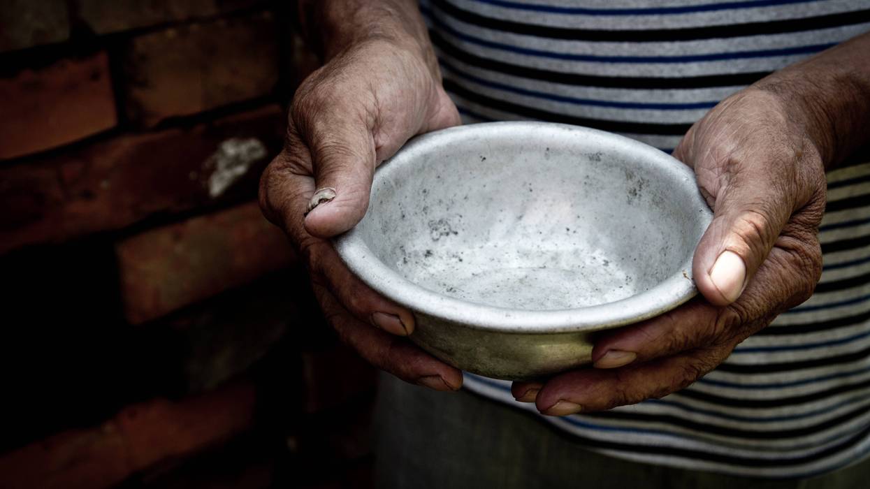 Man holding empty weathered metal bowl, representing food insecurity
