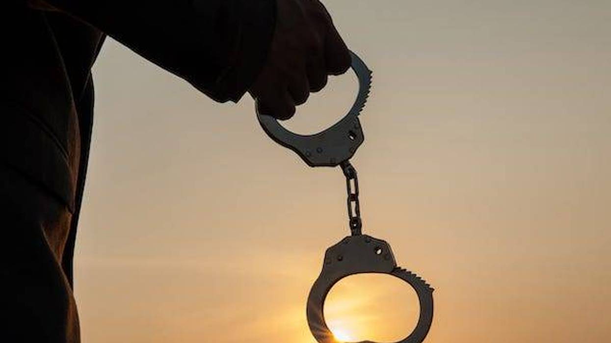 Man holding handcuffs against sunset