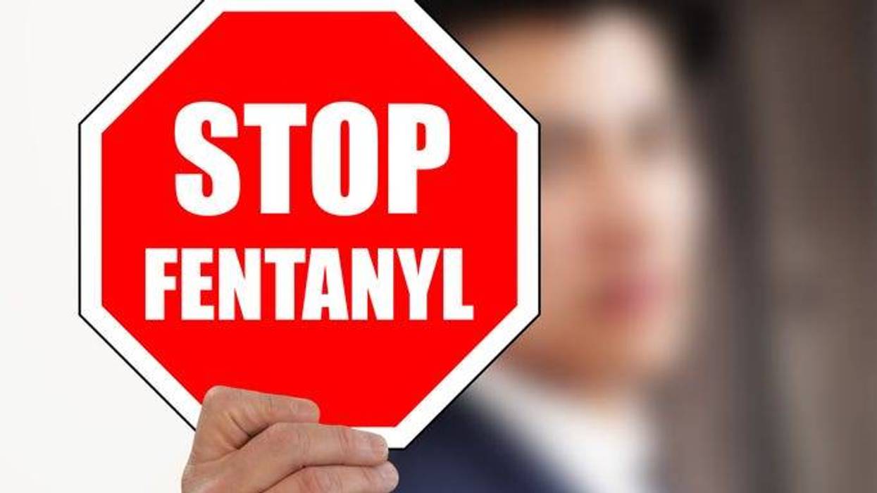 man holding STOP FENTANYL road sign