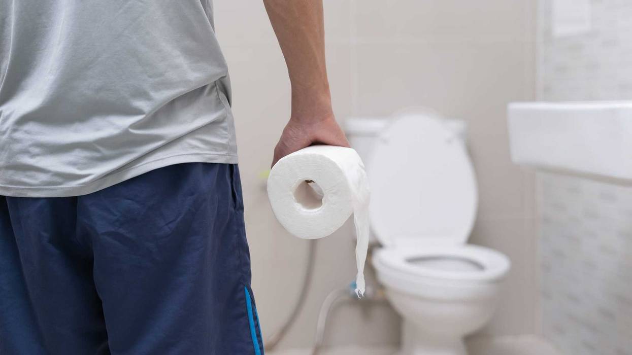 man holding toilet paper in the bathroom
