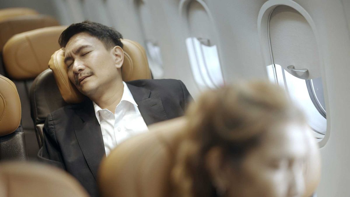 Man in an airplane seat that's reclined.