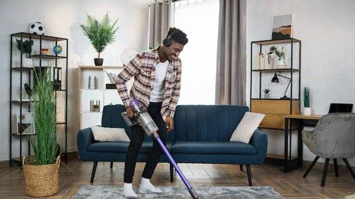 Man in headphones cleaning carpet with vacuum cleaner
