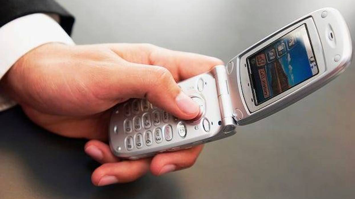 Man in suit holding a flip phone