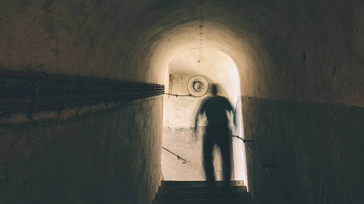 Man is walking through dark underground.