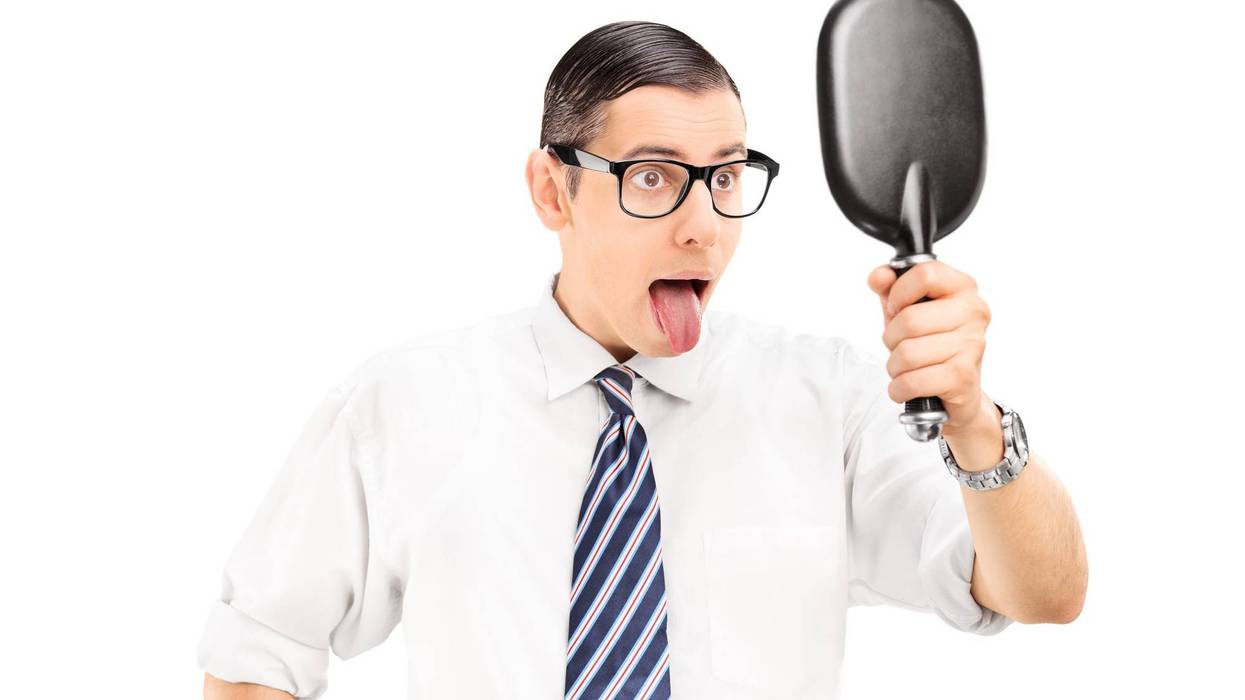 Man looking in mirror and sticking his tongue out