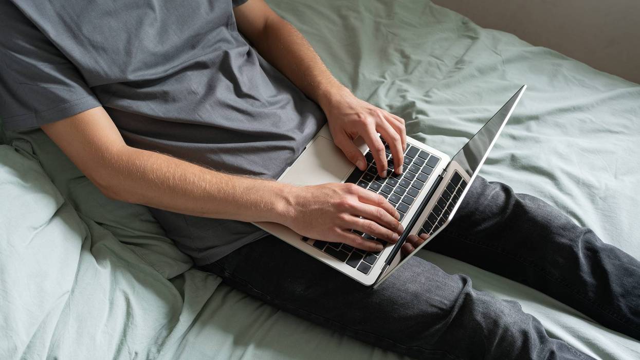 Man on bed working on laptop. Concept of online work or home office