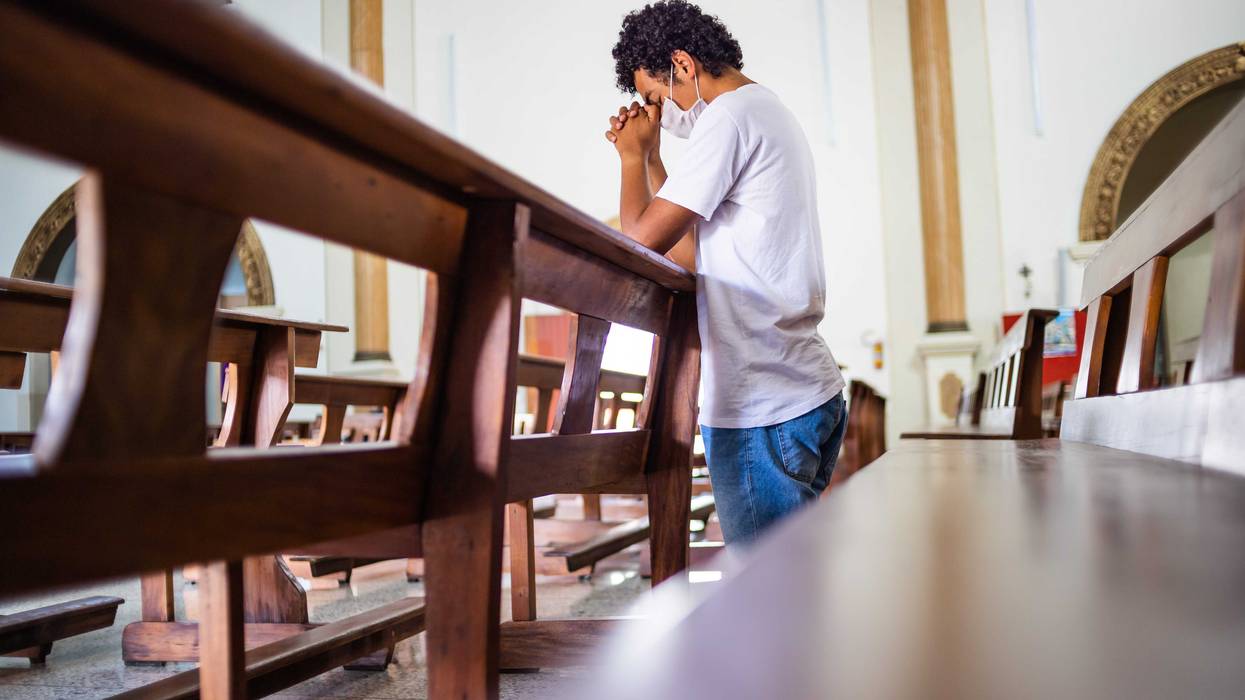 Man praying while wearing a mask.