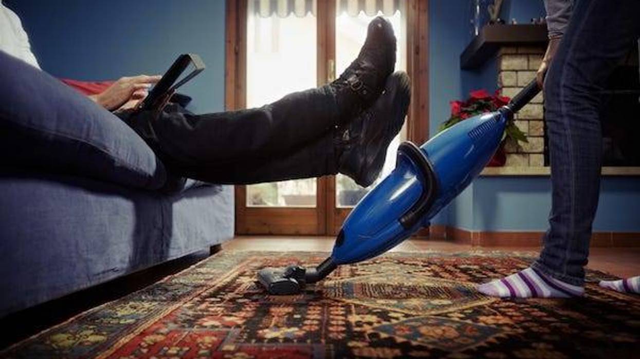 Man relaxing while woman does chores at home