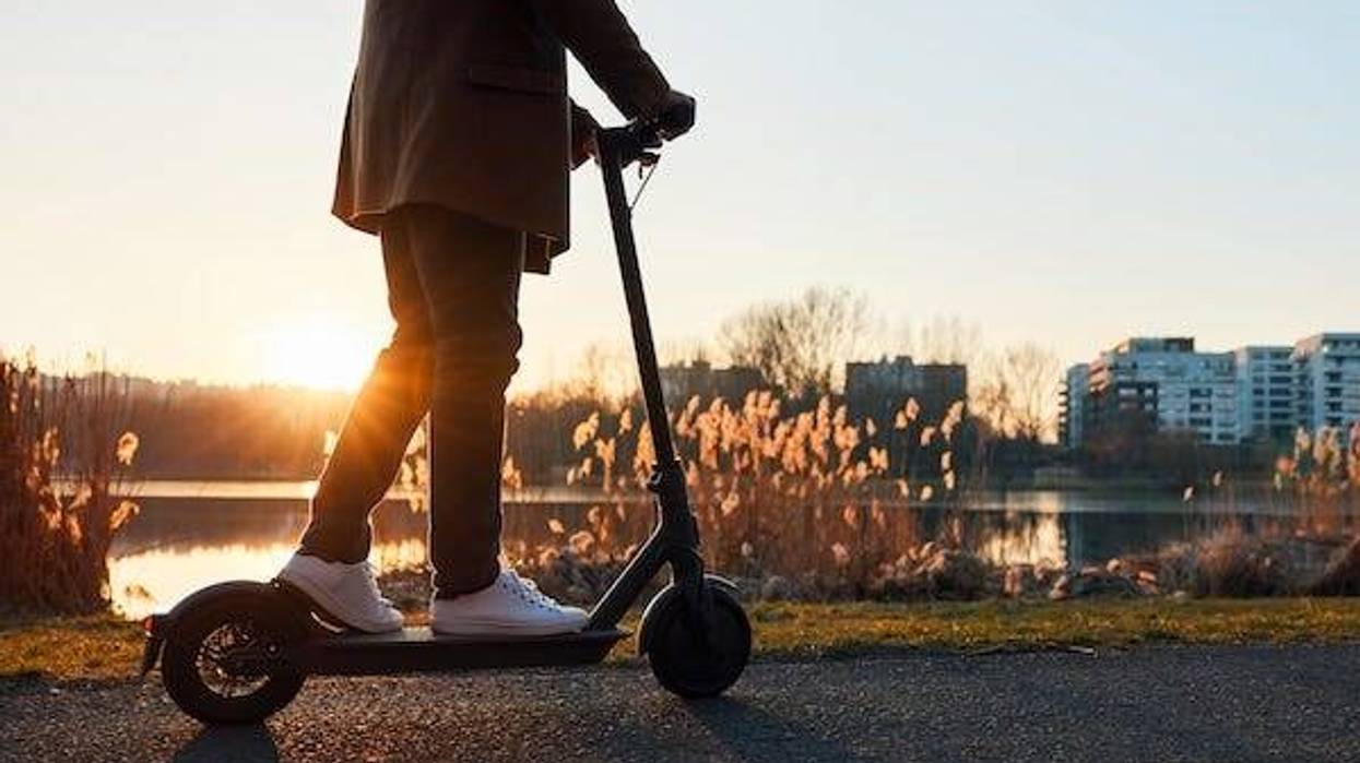 Man riding electric scooter in a park during sunset