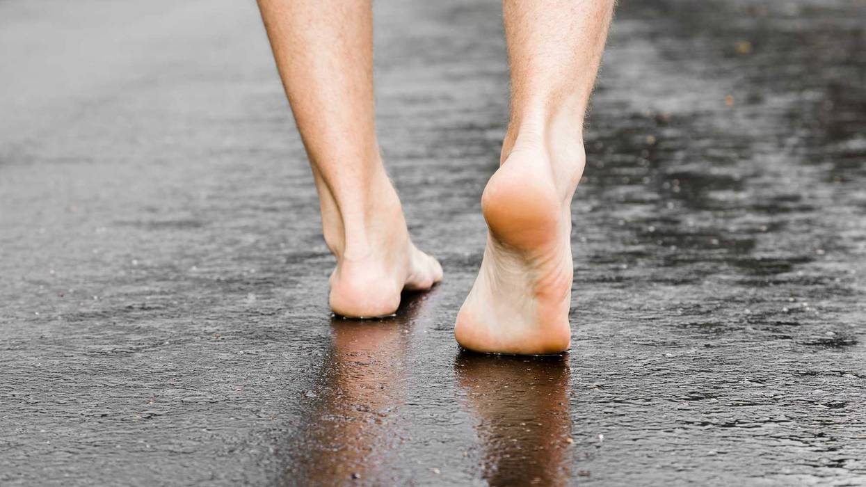 Man's barefoot on the street after rain.
