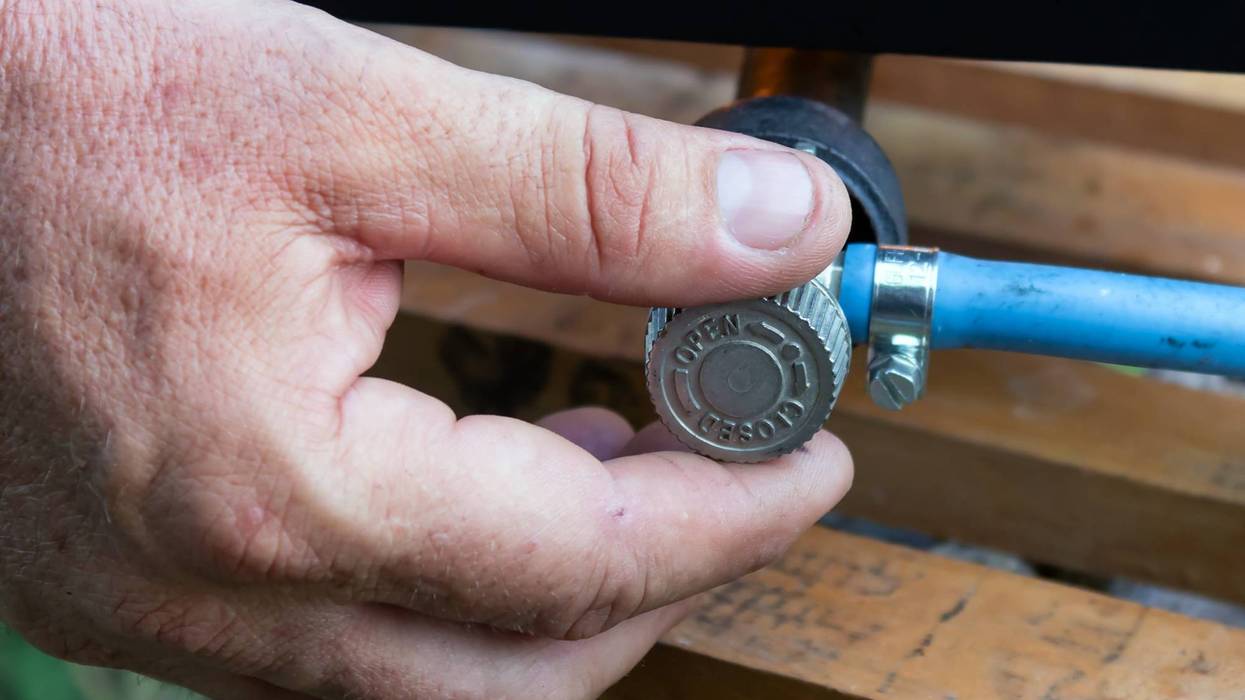 man's hand opens or closes gas valve on gas pipe, closeup